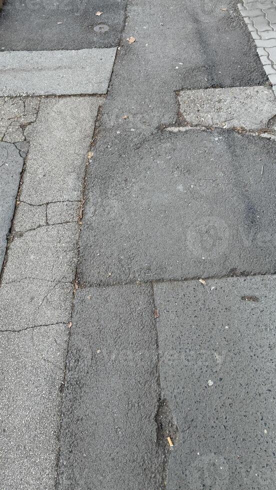 Cracked urban sidewalk with weathered texture symbolizing urban decay, infrastructure challenges, and city life realities photo