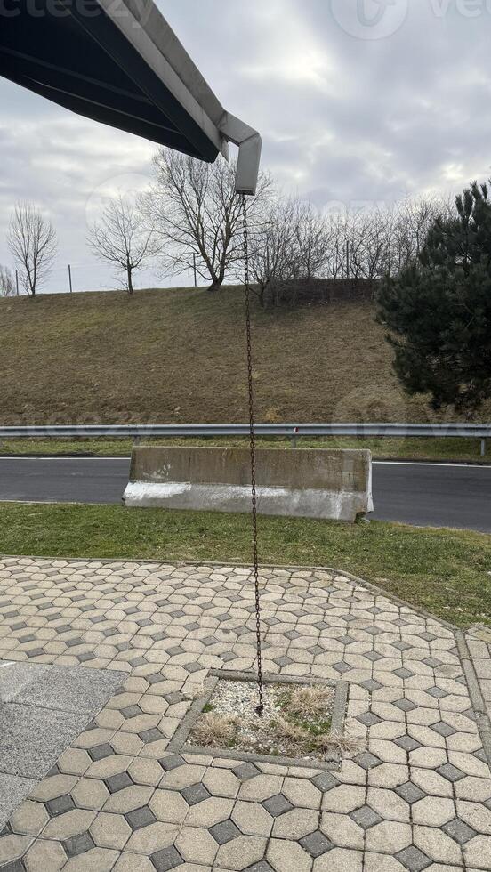 Rainwater stream from roof spout on cloudy day, showcasing sustainable urban design, Earth Day conservation photo