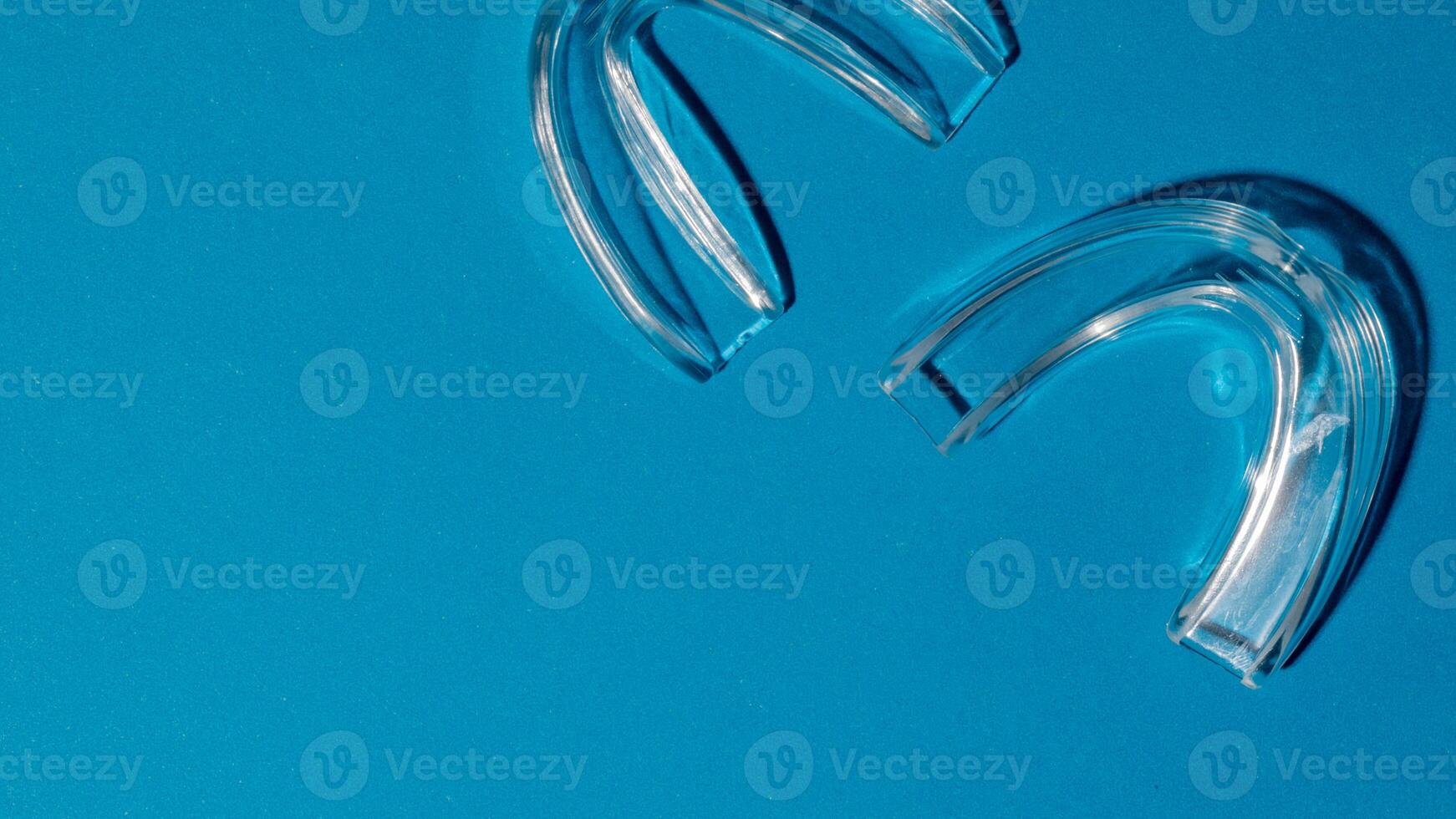 Clear dental aligners on a vibrant blue background, orthodontic care, modern health innovation, dental hygiene focus photo