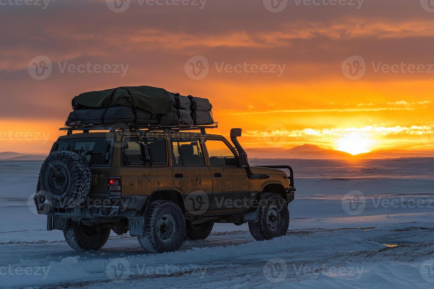 An off-road vehicle is parked on a snowy terrain, showcasing its rugged design against a vibrant sunset. photo