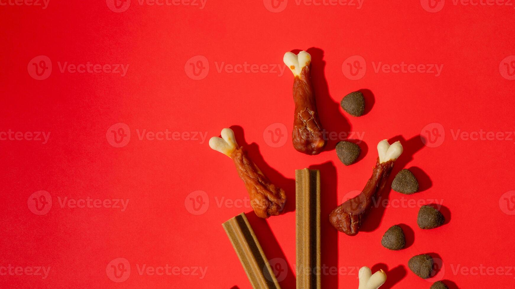 Dog treats arranged creatively on a vibrant red background, pet care, National Pet Day, playful design photo