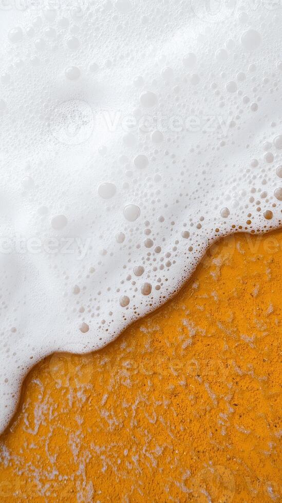 Aerial View of Soft Waves Gently Touching a Vibrant Orange Beach with Texture and Bubbles photo