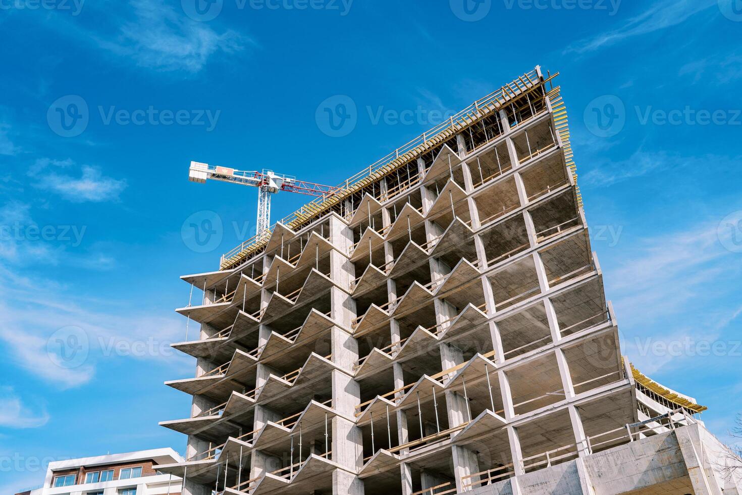 High tower crane builds a multi-storey building with balconies photo