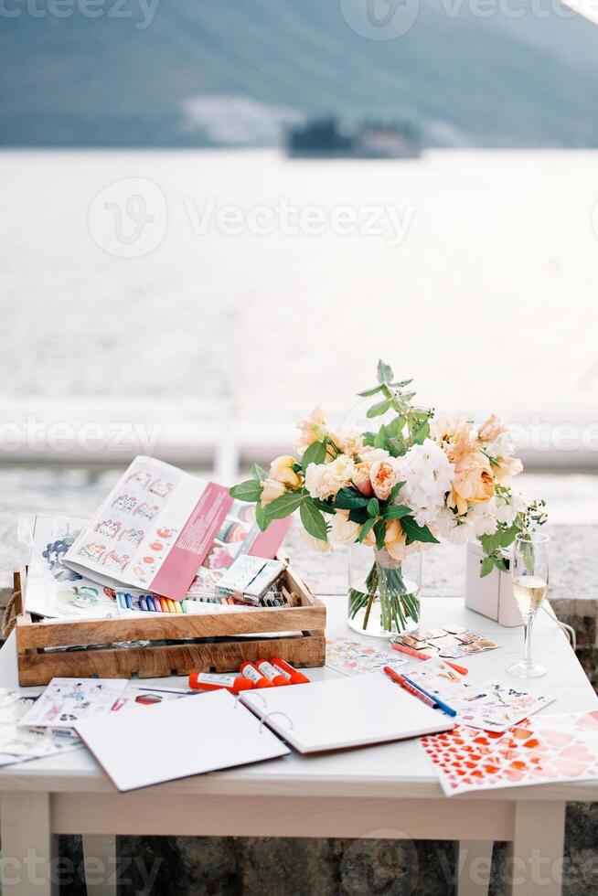Reception table with a journal of wishes, a set of pencils, markers, beautiful stickers and a bouquet of flowers photo