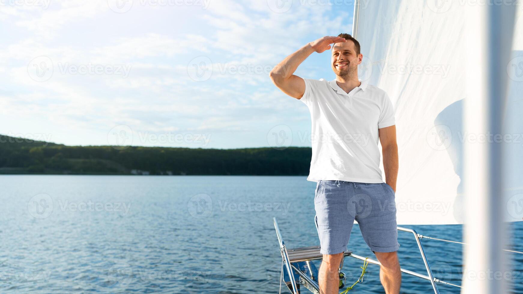 Yacht Sailing. Cheerful Man Standing On Sailboat Deck Looking At Seascapes Spending Summer Day On Water Outside. Dream Vacation, Touristic Adventure Concept. Free Space For Text photo