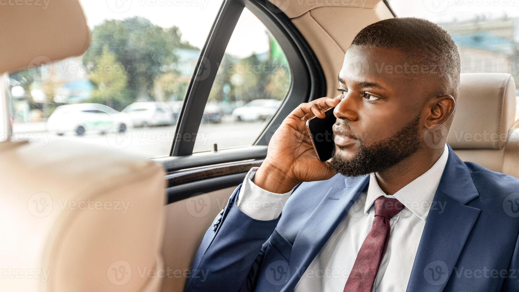 Black manager sitting on back seat in car and using digital tablet, checking email, having phone call, copy space. Handsome african american businessman going to meeting, working on a way to office photo