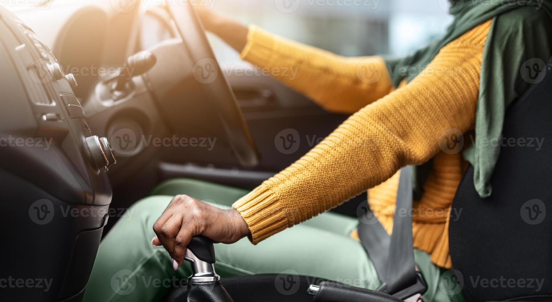 Unrecognizable Black Muslim Lady In Hijab Driving Car, Holding Gear Shift Knob, Smiling African Islamic Woman Enjoying Ride In Her New Vehicle, Selective Focus On Transmission Handle, Cropped Image photo