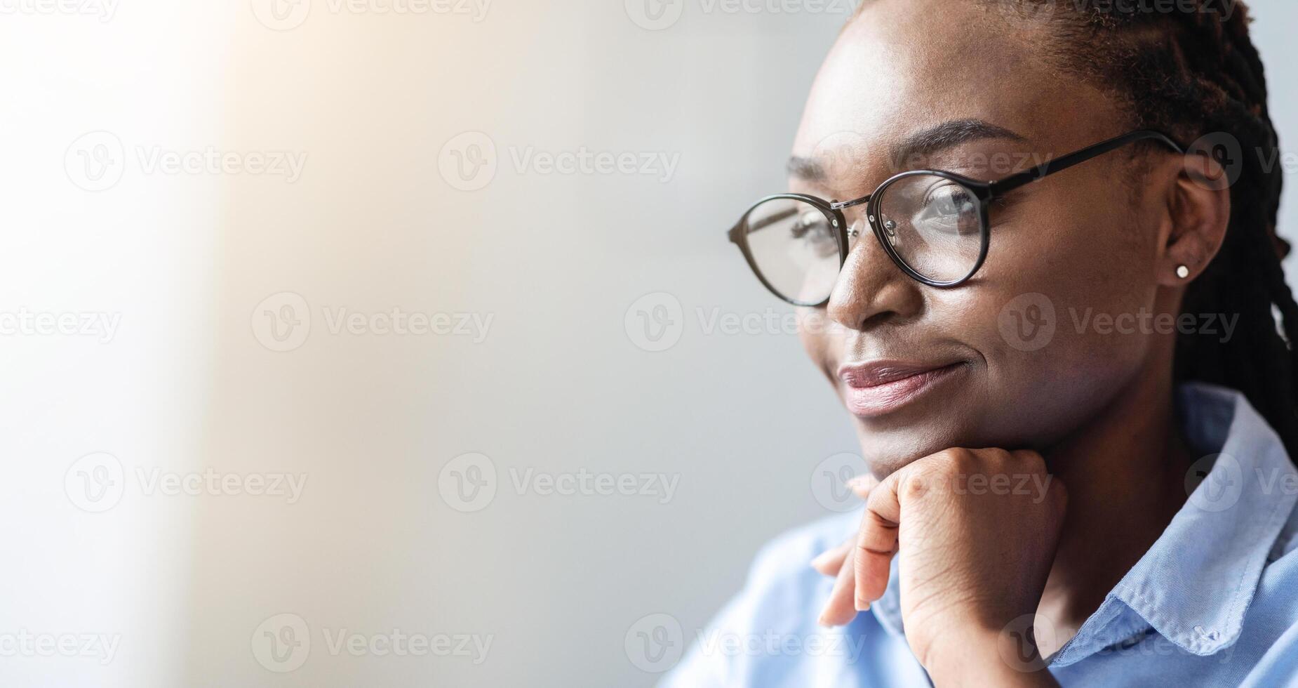 Closeup portrait of pensive black female entrepreneur in eyeglasses looking aside with glad face expression, cropped image with copy space photo