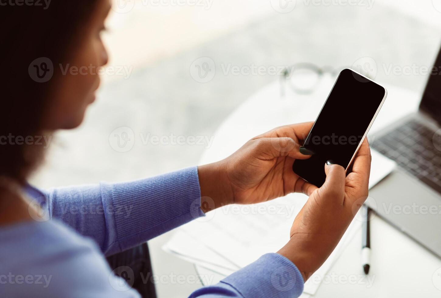 Unrecognizable Black Woman Using Cell Phone With Empty Screen Sitting At Workplace. Selective Focus, Mock Up photo