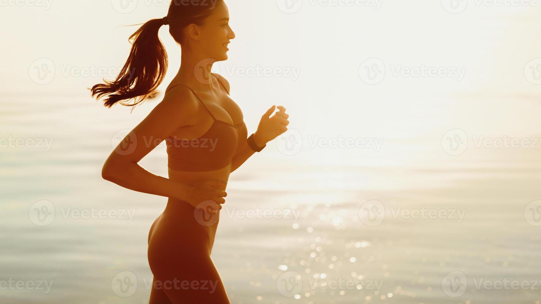 Side view of smiling woman jogging at the seaside in the morning, copy space photo