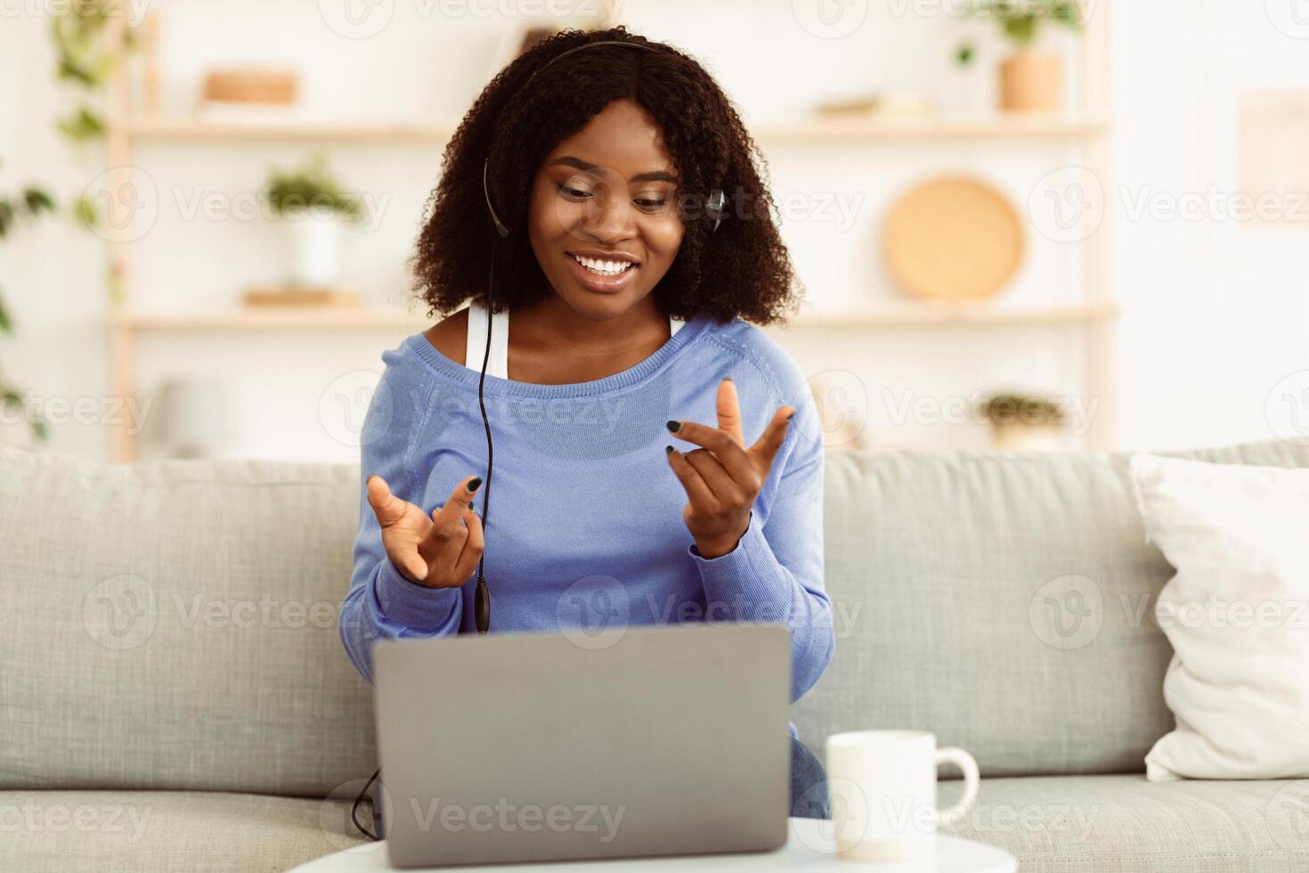Web Conference. Black girl having call on laptop at home office, talking at camera while sitting on sofa photo