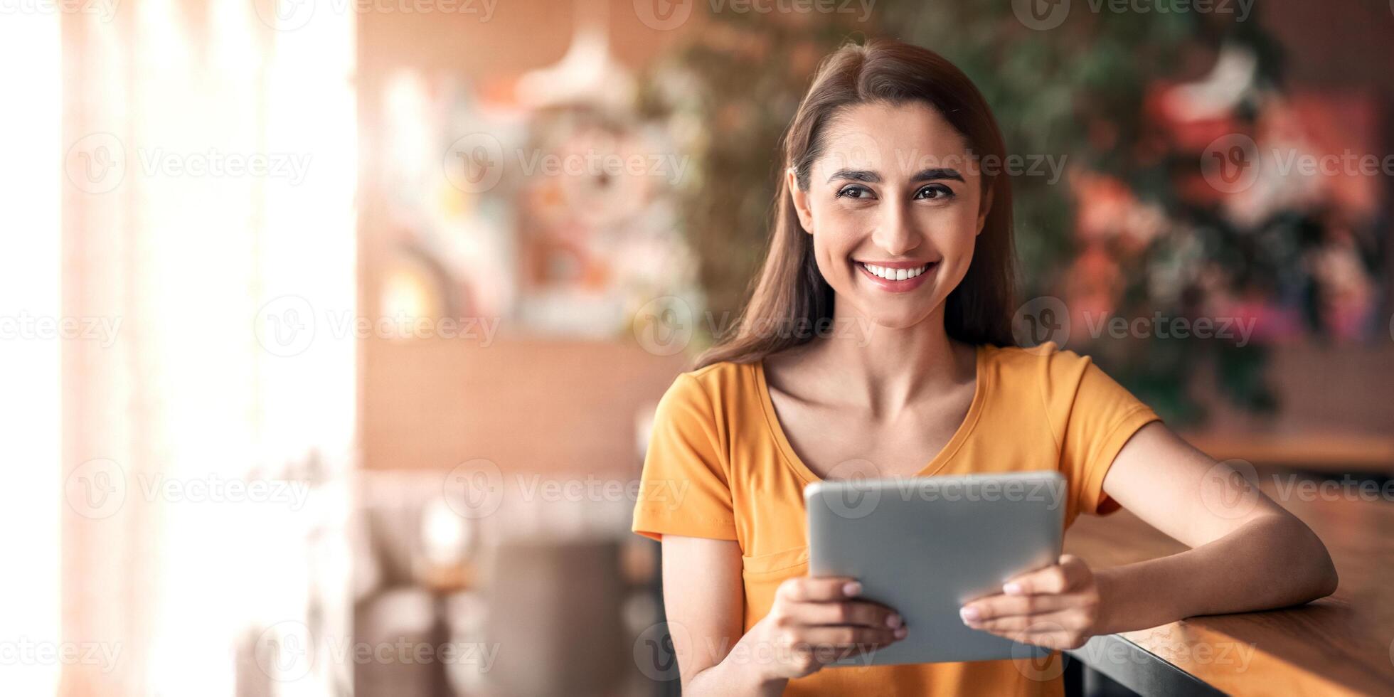 Happy arab lady using digital tablet, sitting at cafe alone, copy space. Pretty young woman with pad smiling at camera, working online at cafeteria, SMM-manager, freelancer, blogger making her job photo