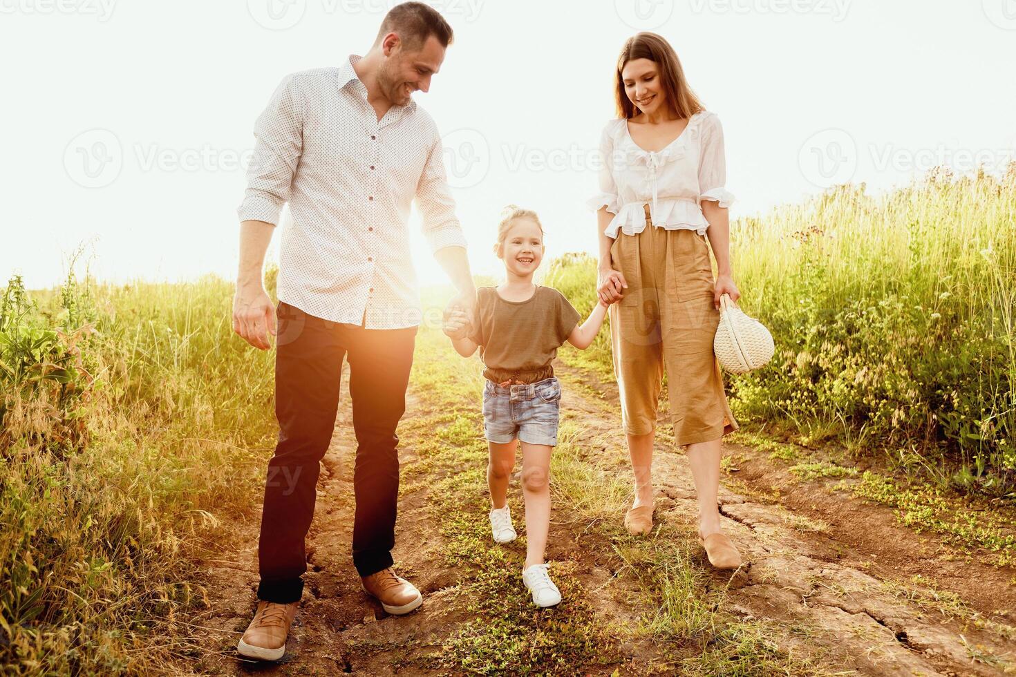Concept Of A Happy Family. Cheerful parents walking with their kid and holding her by hands photo