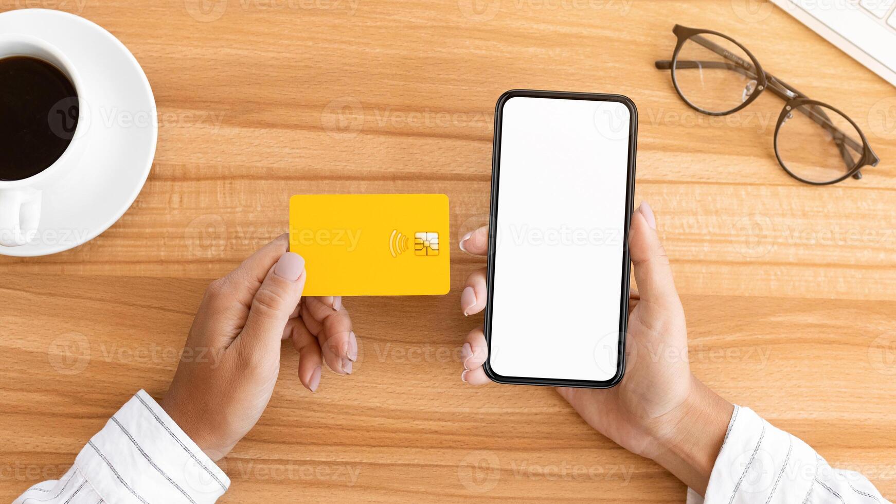Easy Pay. Above view of woman using credit card and blank smart phone with white mock up, wooden table background photo