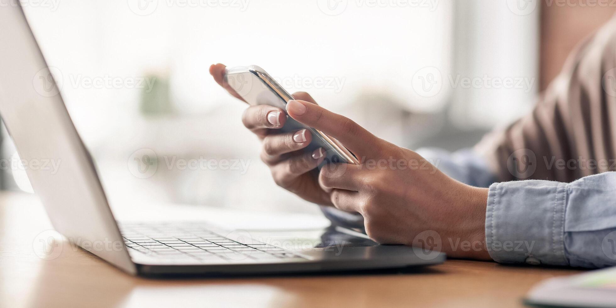 Female hands holding mobile phone and using laptop, freelancer working at cafe, cropped, copy space photo