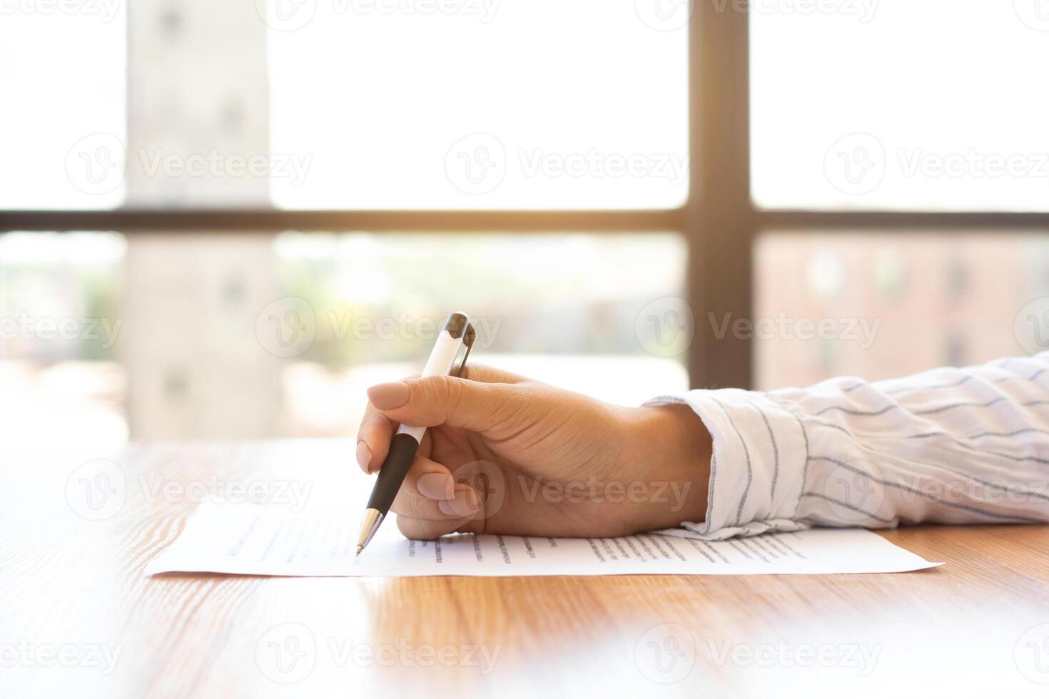 Side view of businesswoman signing a document after reading the agreement in office photo