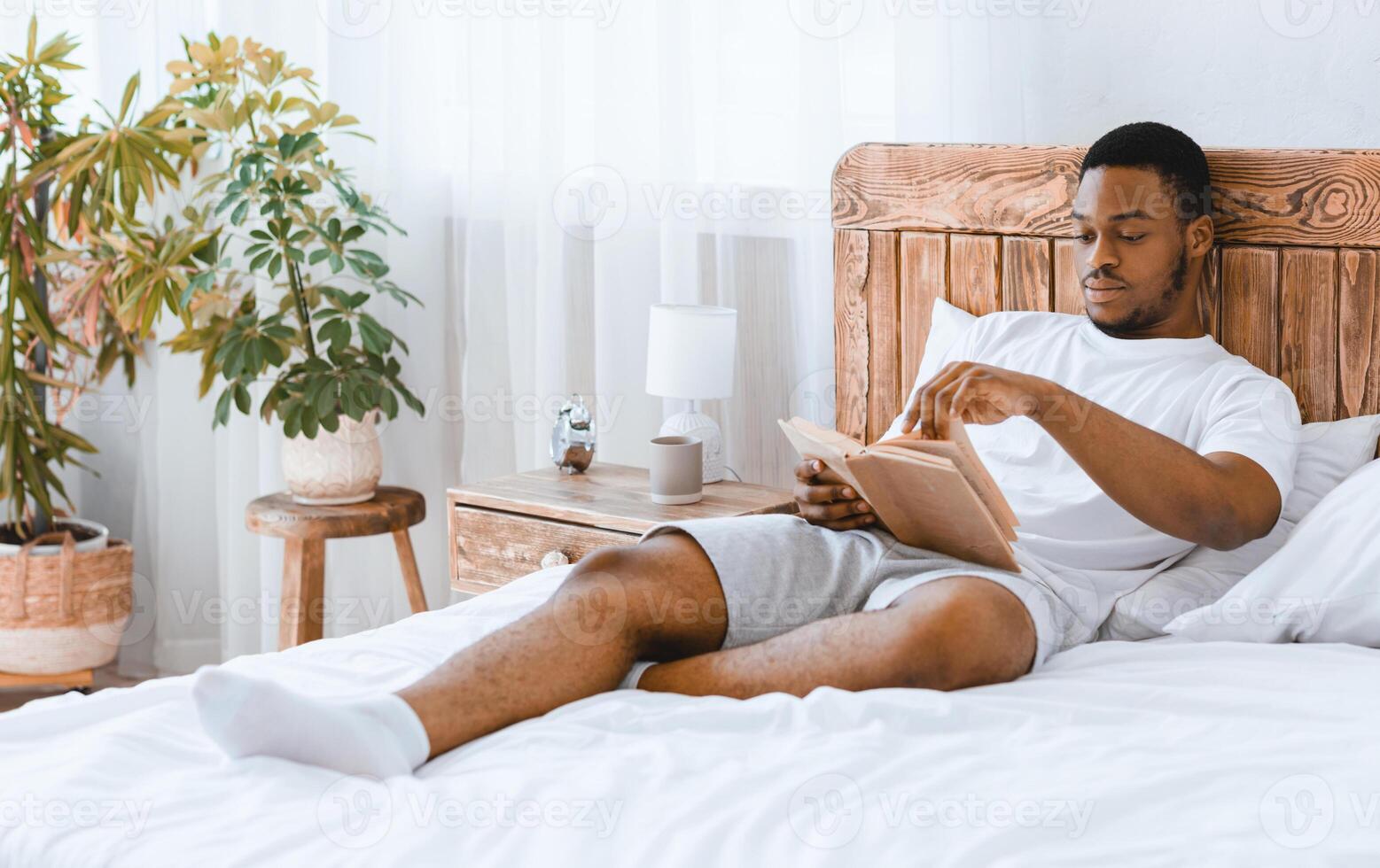 Read More. African American Man Reading Bestseller Book Lying In Cozy Bed Relaxing In Bedroom At Home. Black Guy Enjoying Lazy Morning. Weekend Leisure And Relaxation Concept photo
