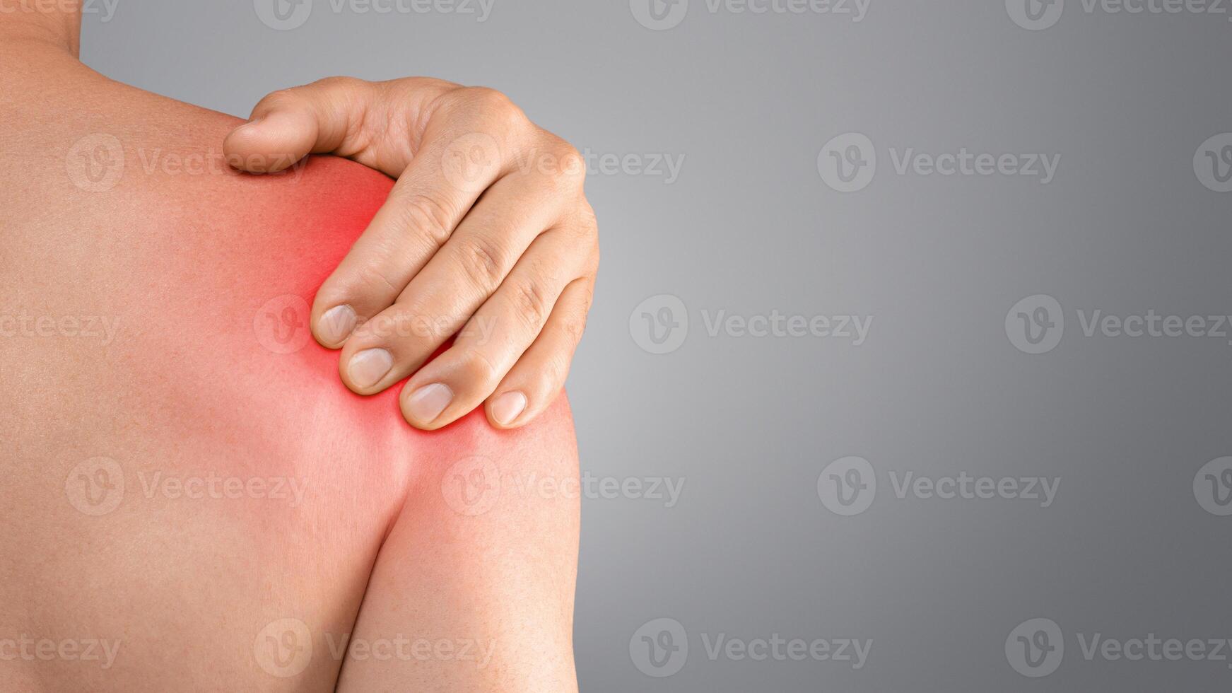 Closeup of topless man suffering from shoulder pain injury, rubbing sore zone over grey studio background, copy space, cropped. Healthcare and medical concept, sports traumatology and orthopedics photo