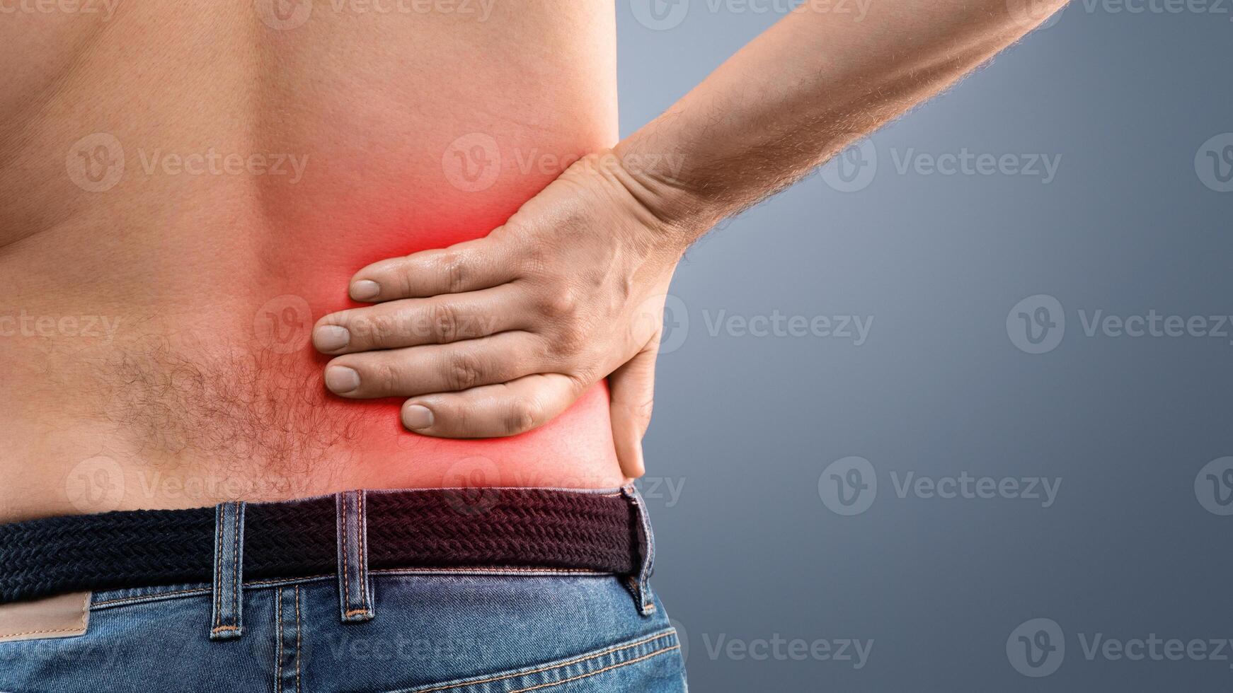 Closeup of unrecognizable topless man touching his loin zone highlighted with red, suffering from chronic or acute kidney disease, grey studio background, copy space. Healthcare concept photo