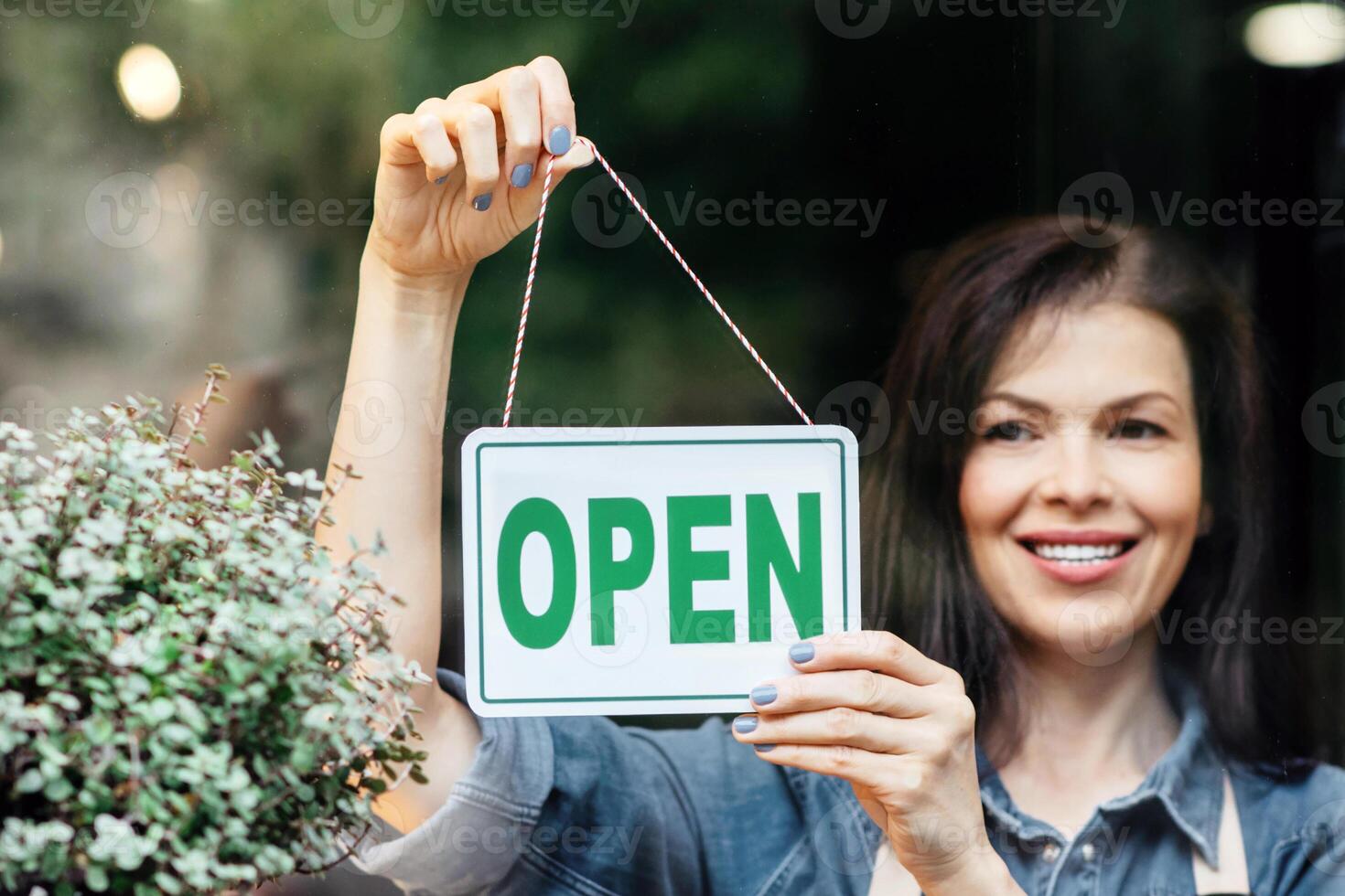 Good morning and start of working day. Happy girl opening florist shop and turns nameplate with inscription open, copy space photo