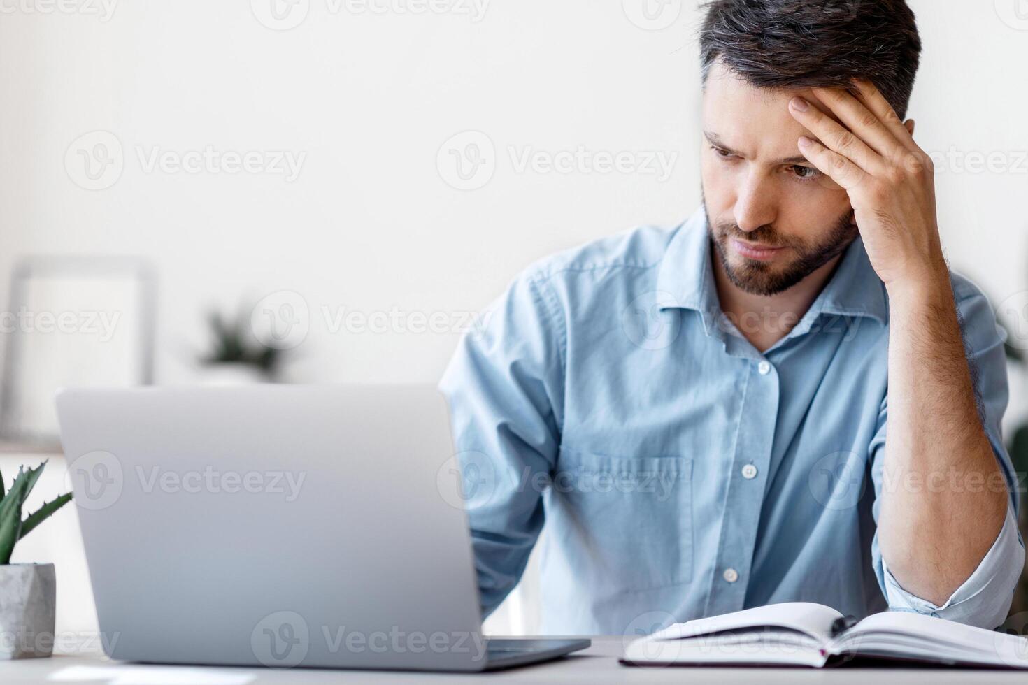Concentrated Male Entrepreneur Looking At Laptop Screen While Working On Project In Modern Office, Handsome Businessman Sitting At Desk With Computer, Thinking About Business Solution, Copy Space photo