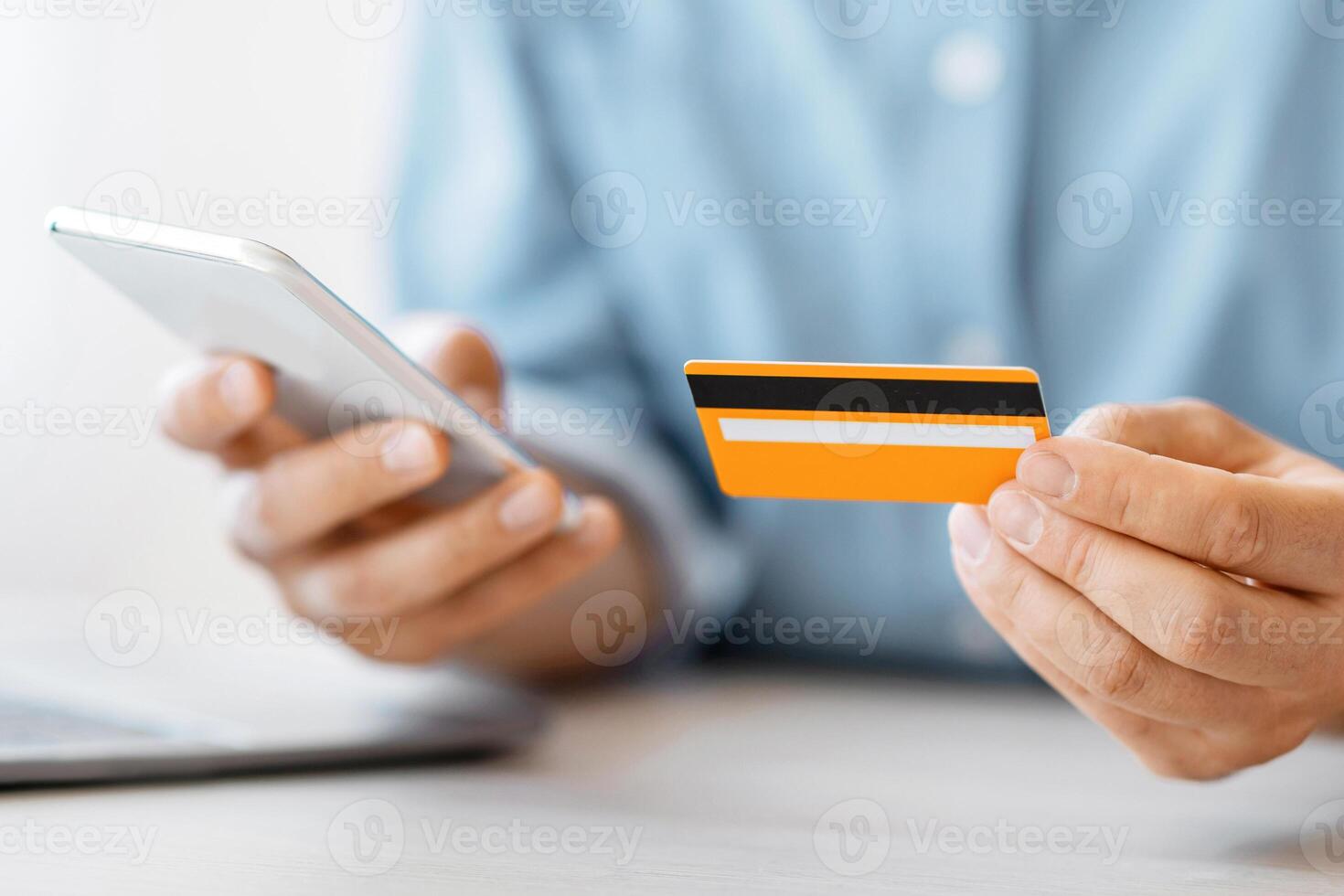 Unrecognizable man using smartphone and credit card in office, paying bills online, using mobile application for money trasfers, closeup photo