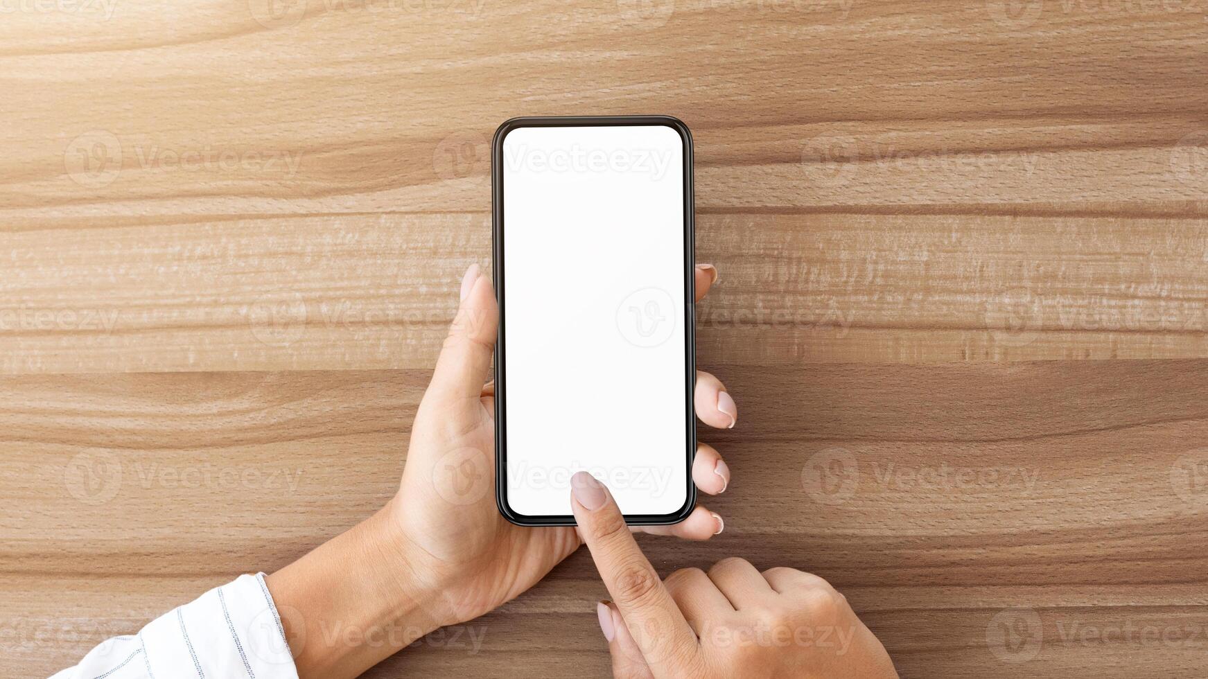 New App. Top view of girl holding smart phone with white mock up screen, touching with finger, copyspace photo