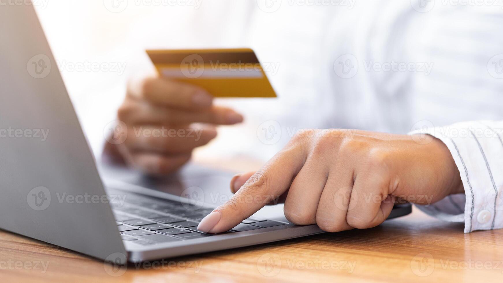 Unrecognizable millennial person shopping in internet on personal computer, using credit card to pay, closeup photo