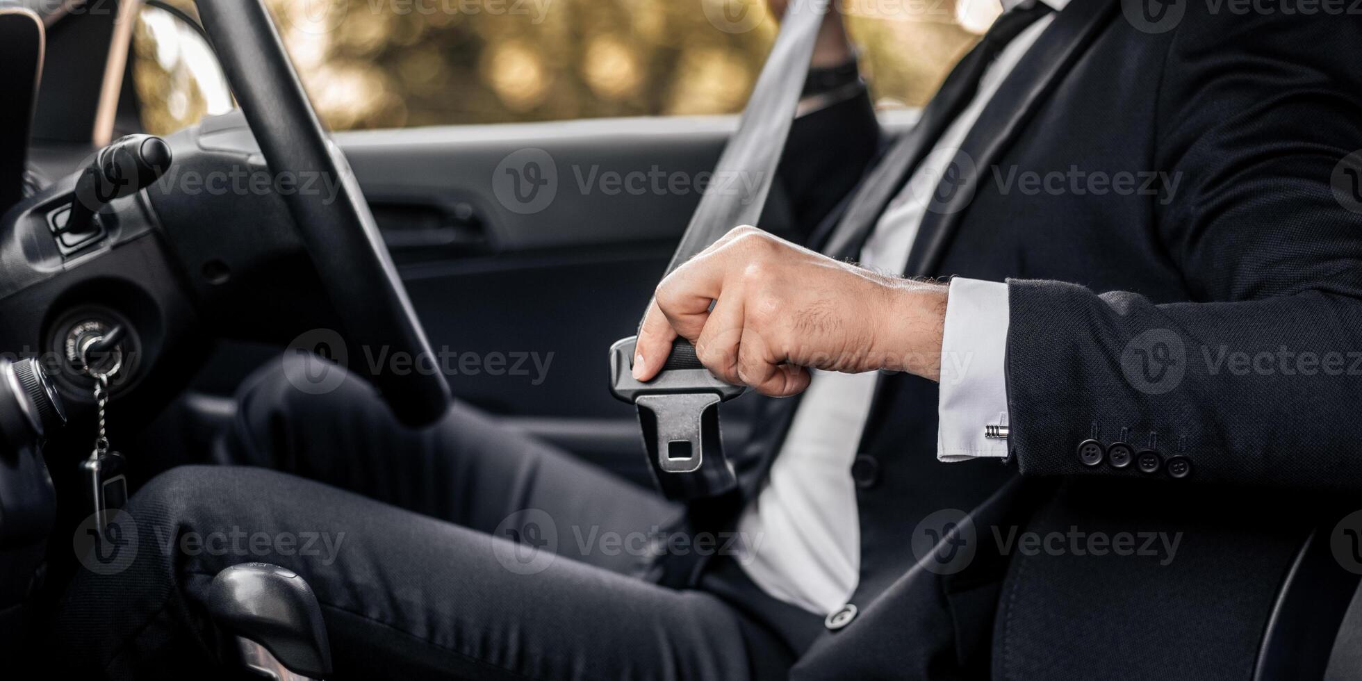 Driving safety concept. Unrecognizable businessman fasten seat belt in his car, ready to go to office. Man in stylish suit putting on his seatbelt before driving car to airport, cropped photo