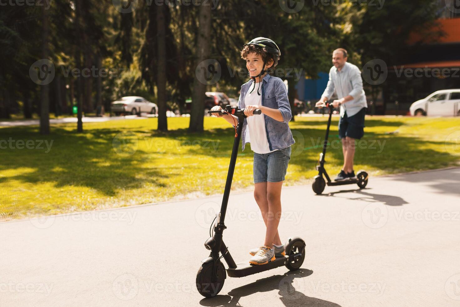 Time With Family. Laughing son using motorized kick scooter with his dad on a sunny day, copy space photo