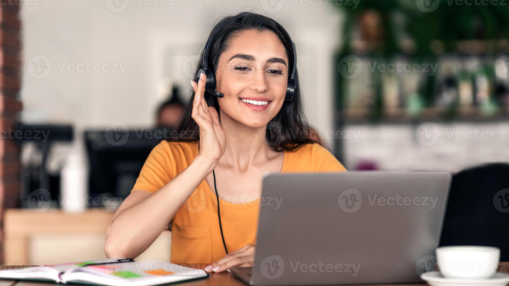 Young arab woman having job interview online, sitting at cafe, using laptop, copy space photo
