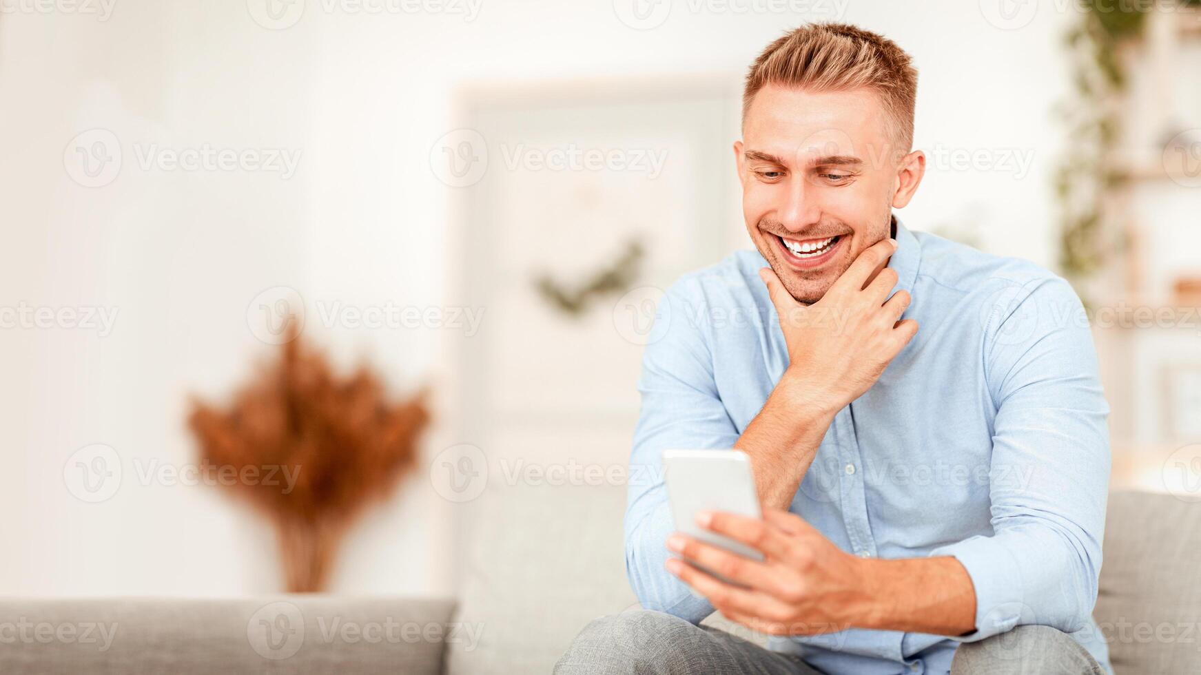 Good News. Portrait of happy man using his cell phone, touching chin, free space, selective focus photo