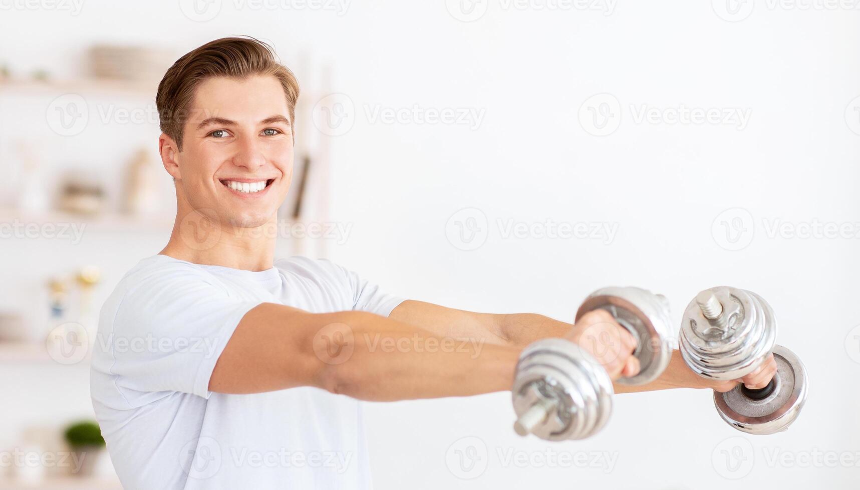 Coach makes recording for sports blog. Happy man doing exercises with dumbbells in living room interior photo