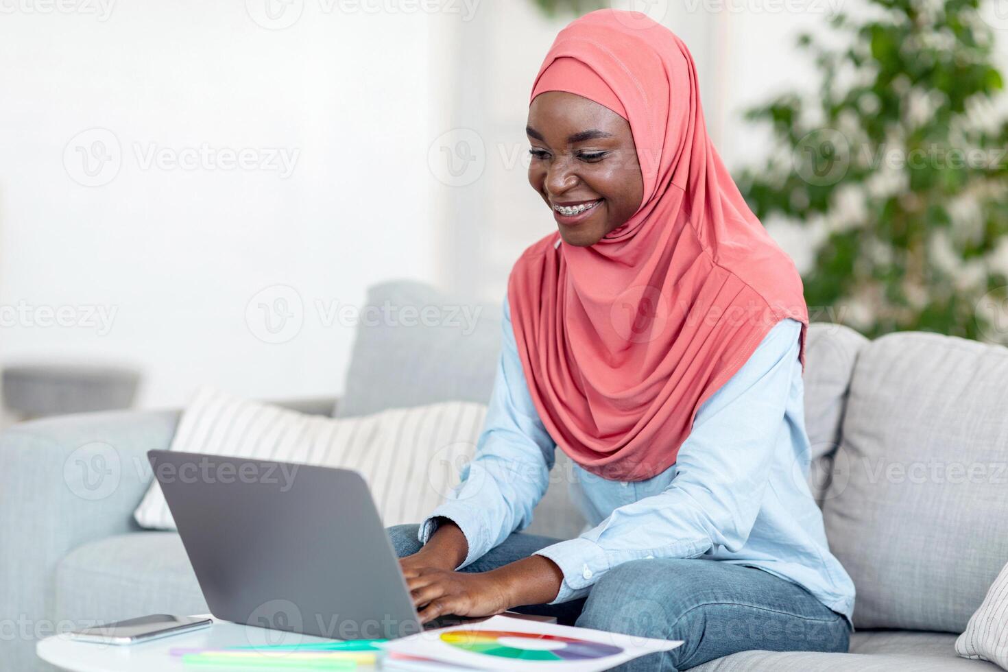 Freelance Career Concept. Black Muslim Woman In Hijab Working On Laptop At Home, Looking At Computer Screen, Typing On Keyboard, Doing Online Job Or Studying, Having Distance Learning, Free Space photo