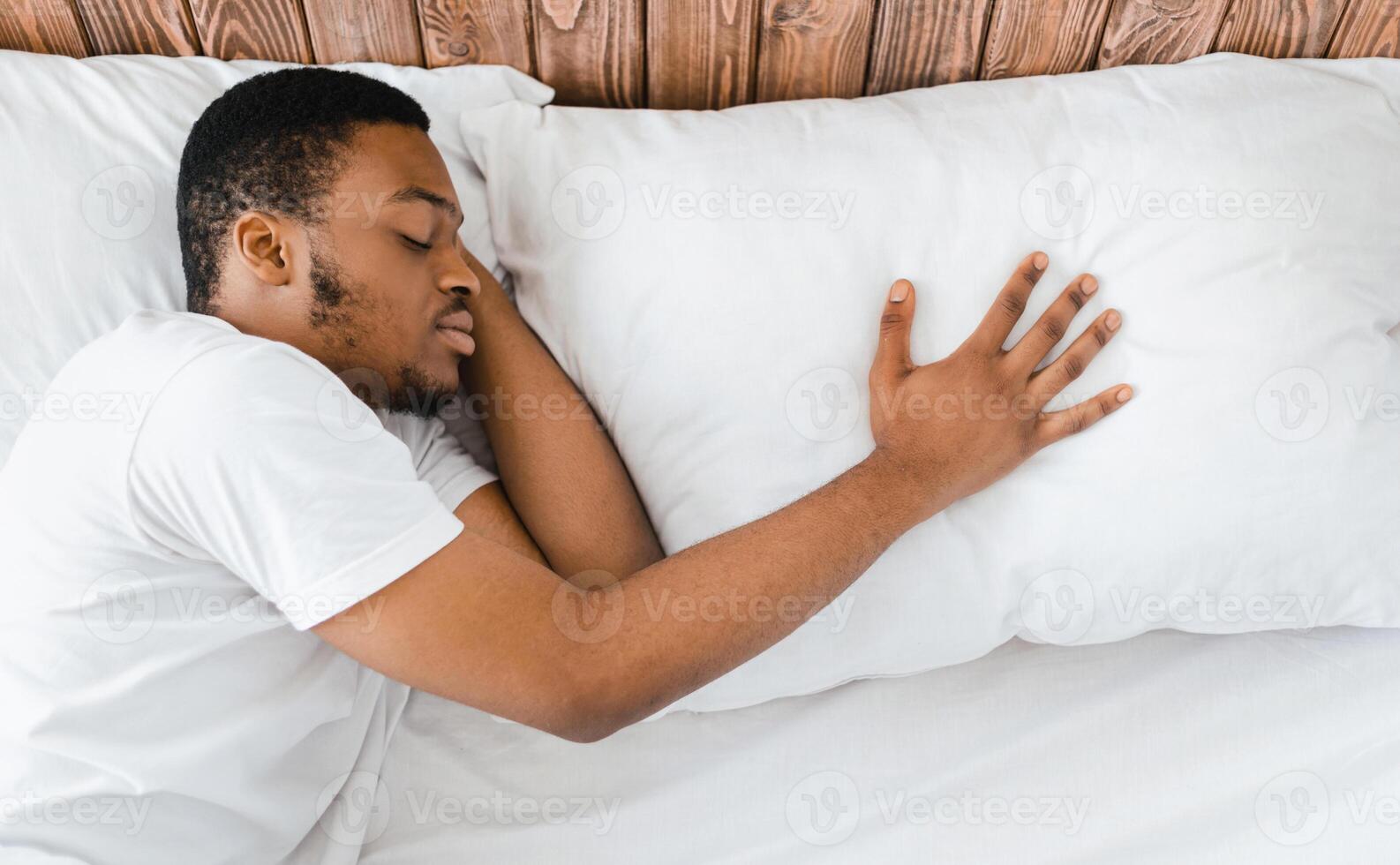 Single African American Man Sleeping After Breakup Alone Lying In Bed, Touching Pillow, Suffering From Loneliness After Divorce At Home. End Of Relationship, Separation Concept. Above View photo