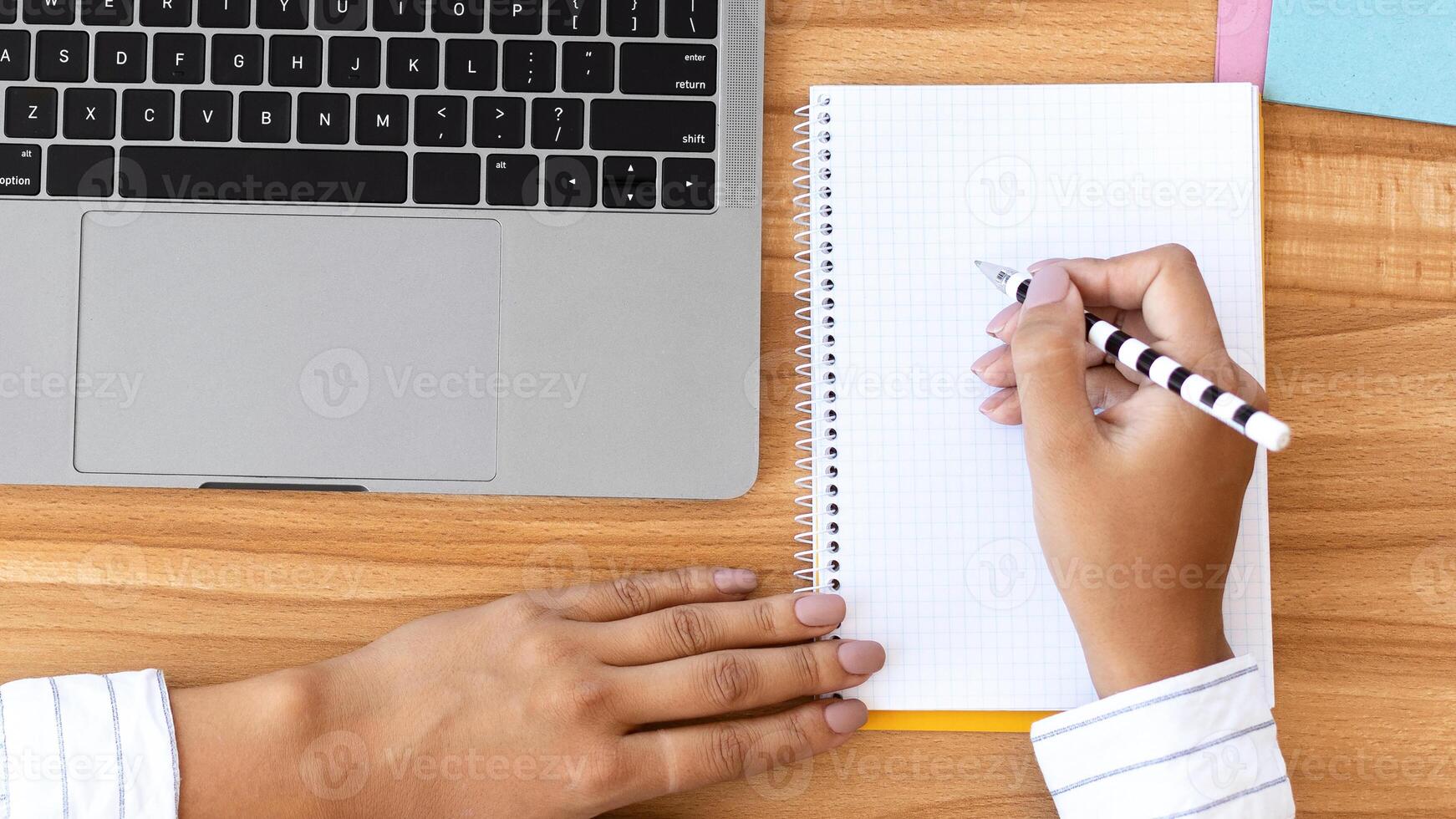 Workspace. Unrecognizable businesswoman working at laptop and writing in notebook in modern office, top view, copy space photo
