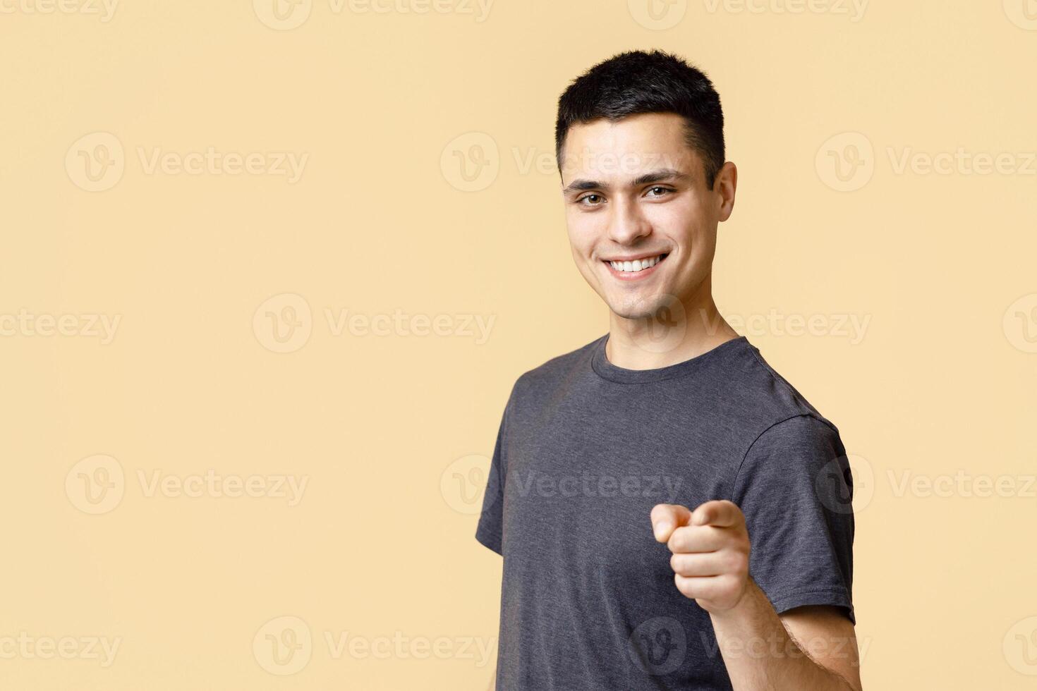 Cheerful man in casual clothes speaks happily at you, chooses to compete, has positive expression. Handsome smart student making choice isolated on light background, empty space, studio shot photo