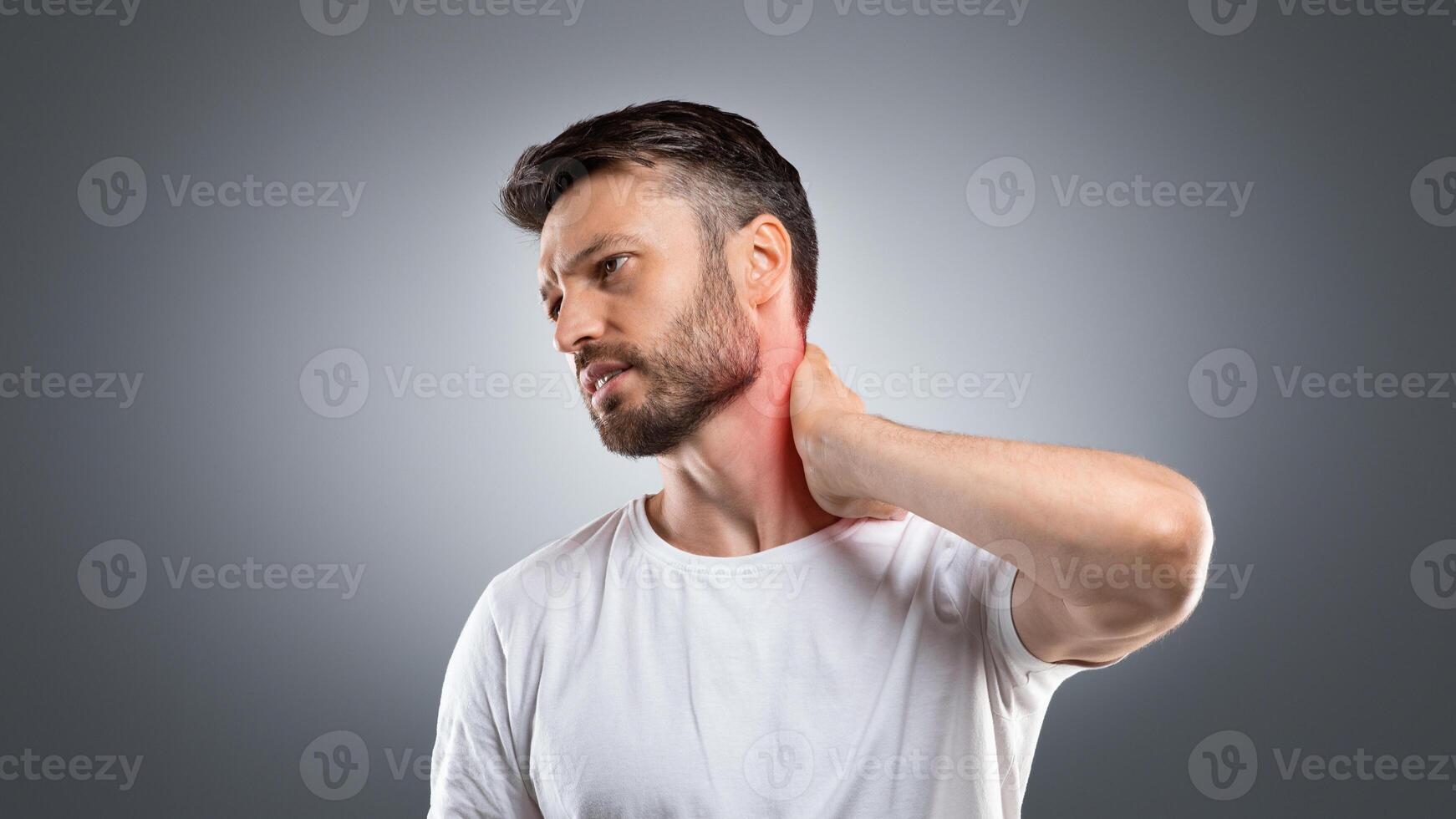 Tired middle aged man touching inflammated zone on his neck, having office syndrome, grey studio background, copy space. Man suffering from cervical osteochondrosis, rubbing lightened with red neck photo