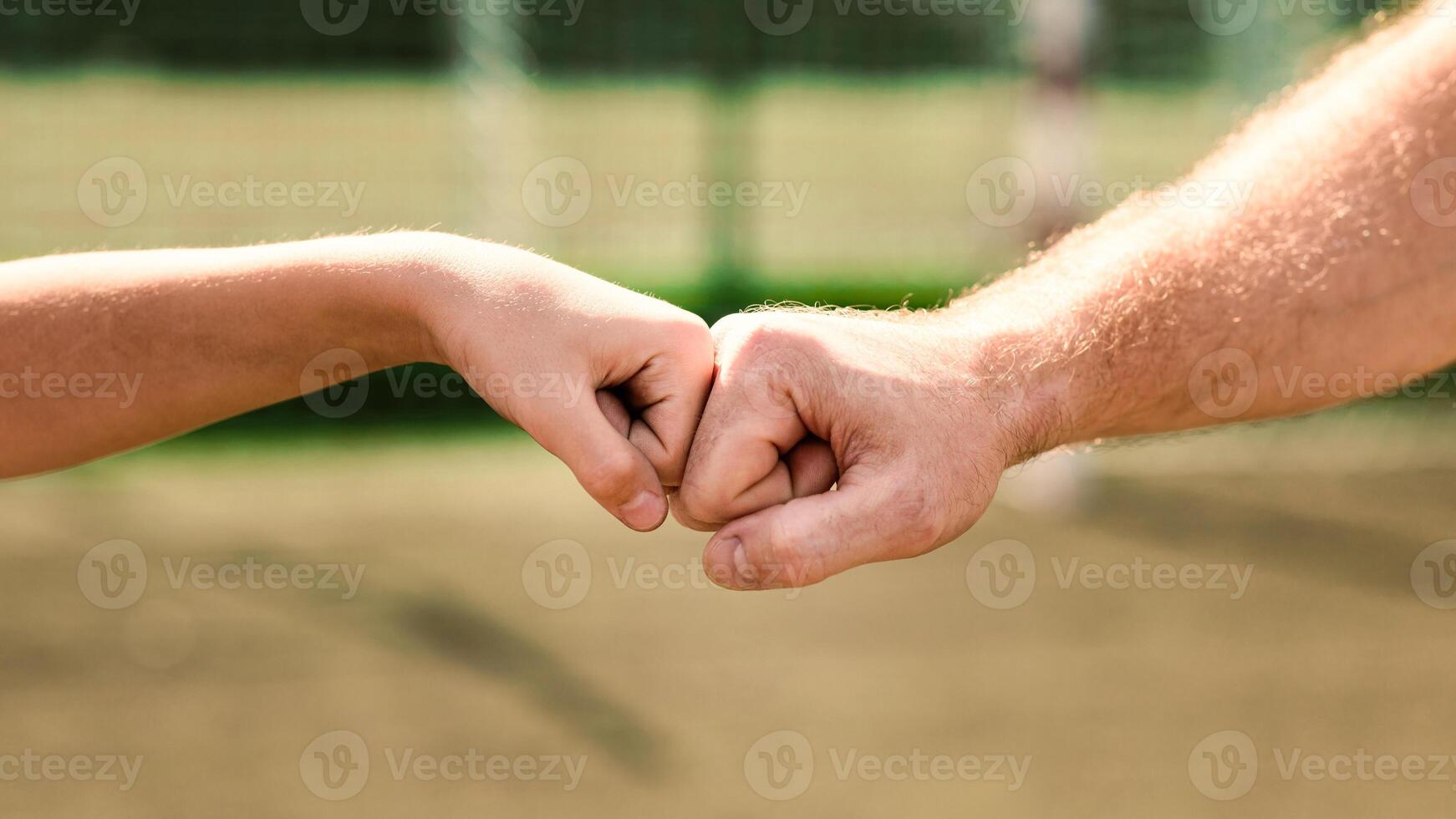 Support Concept. Man giving fist bump to kid in nature background, power of teamwork, selective focus photo