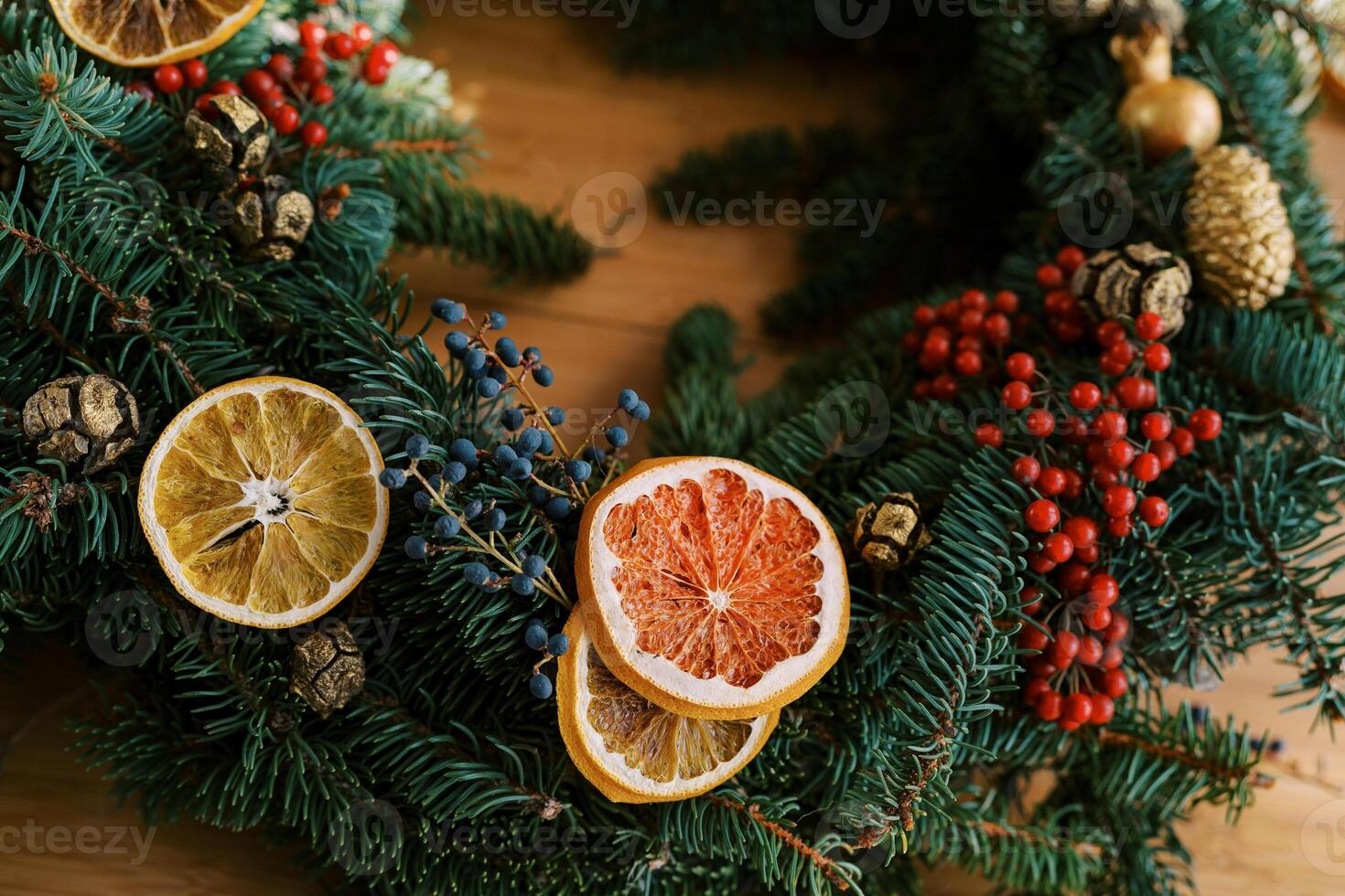 Christmas wreath is decorated with red and blue berries and dried orange slices. Cropped photo