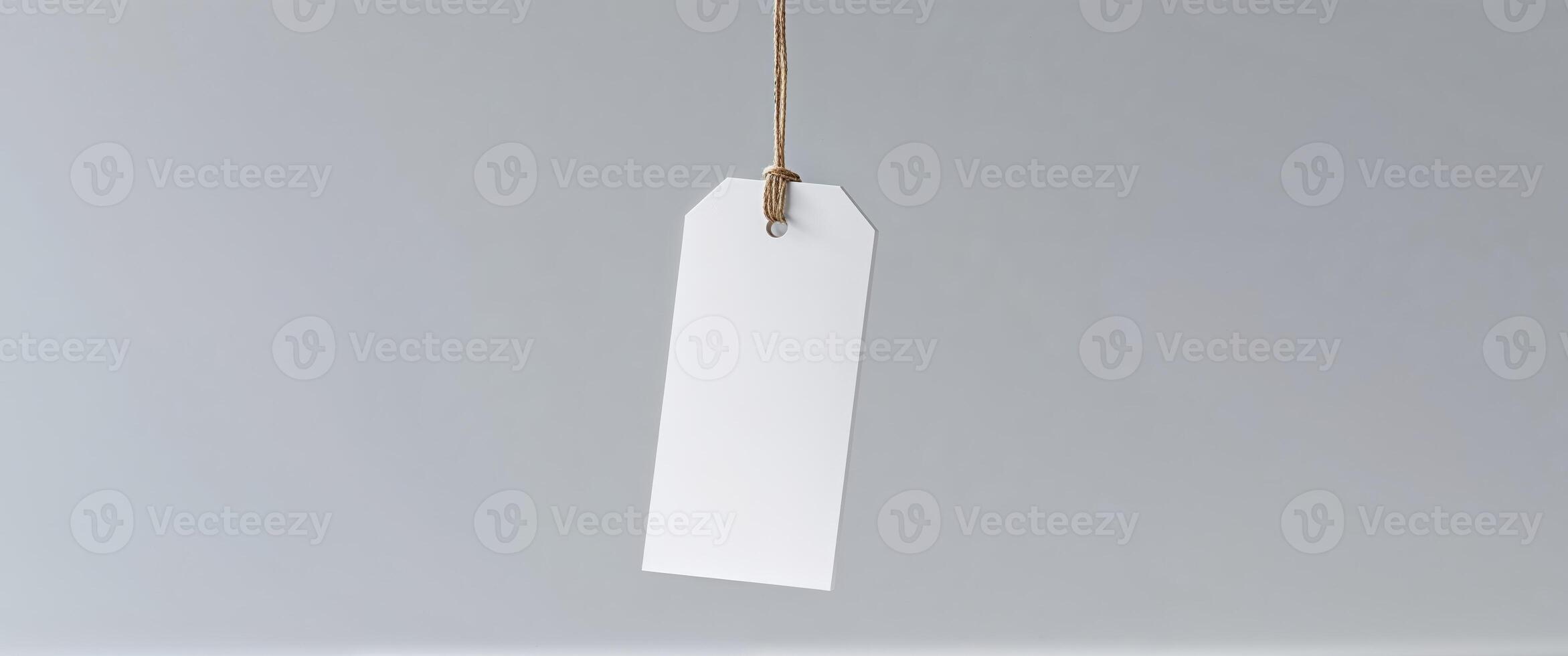 Blank white paper tag hanging from string on white background photo