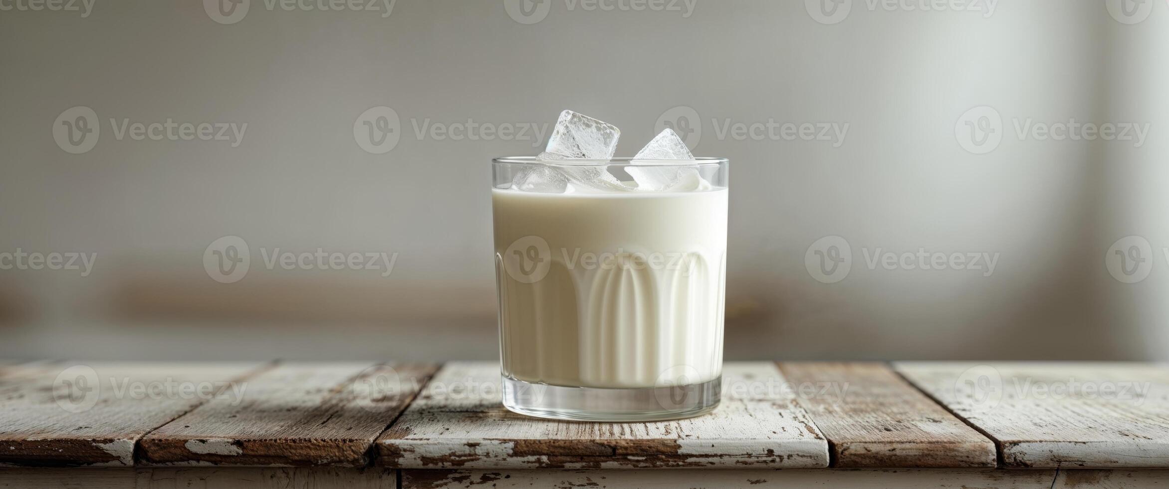 Refreshing creamy drink with ice on wooden counter photo