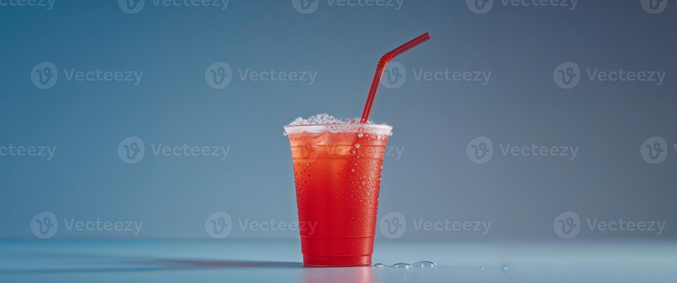 Refreshing Cold Drink in a Red Cup with Straw and Condensation on a blue background with copy space. photo