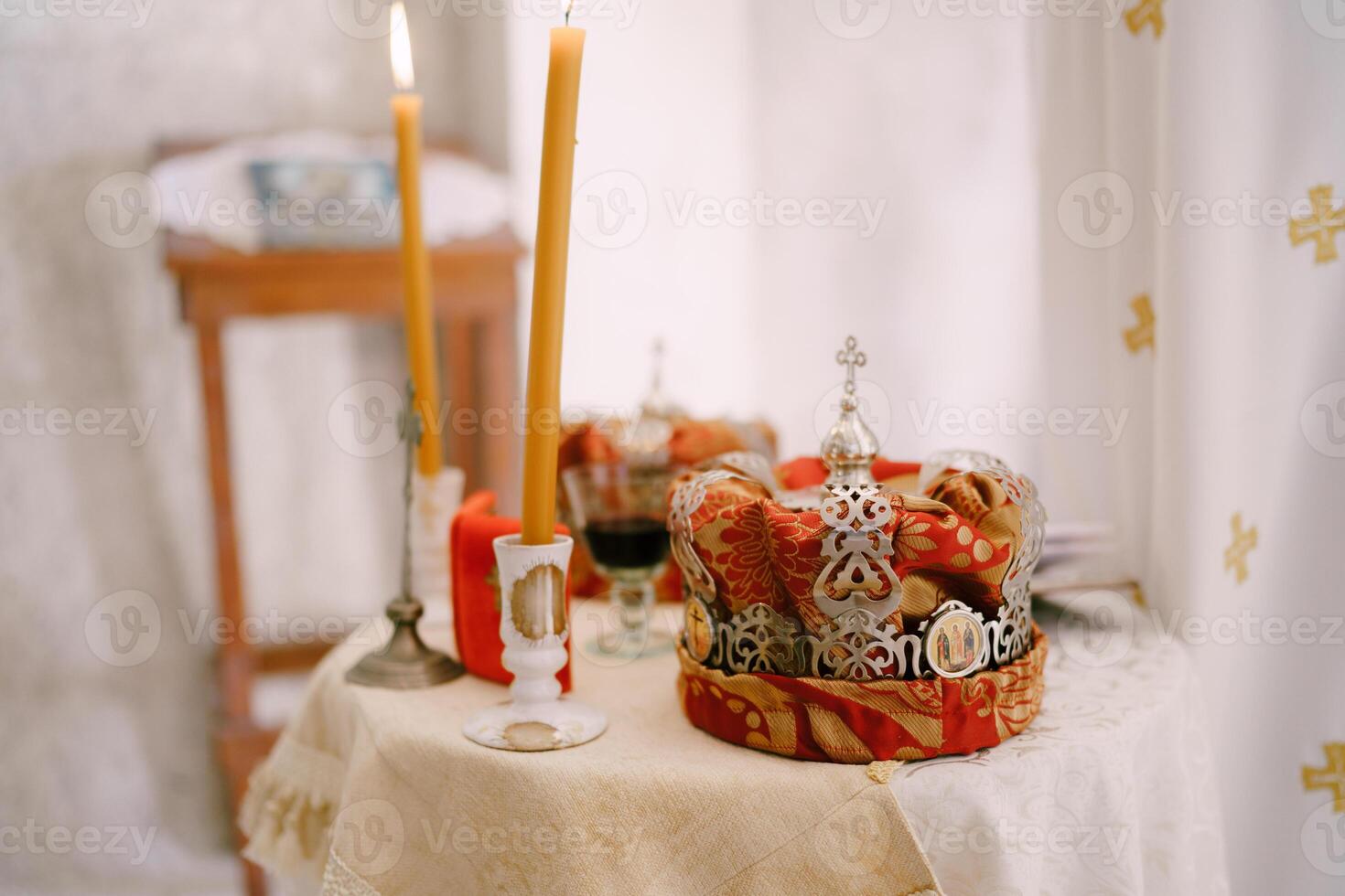 Lighted candles in candlesticks on the table near the wedding crowns in the church photo