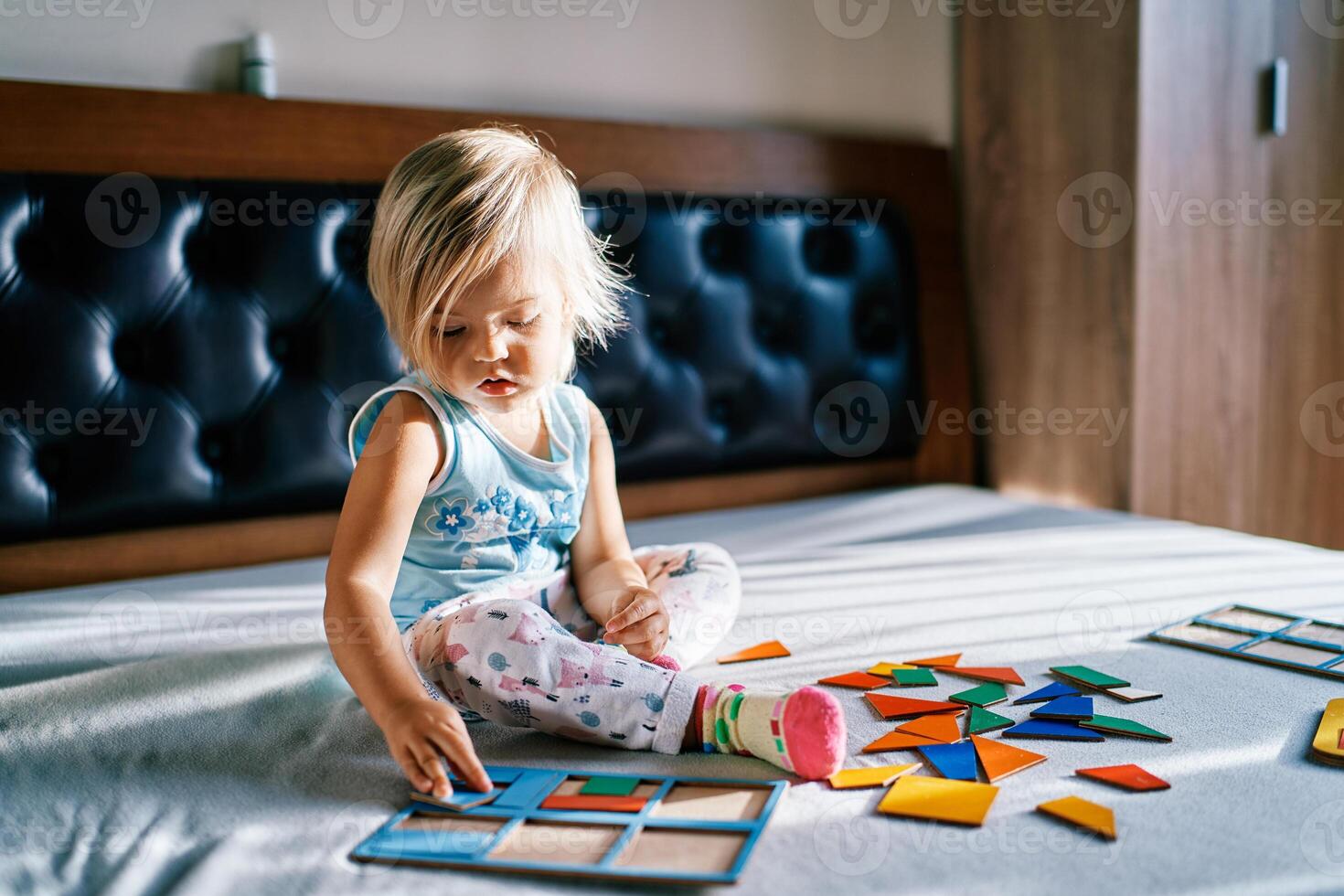 Little girl puts together a colorful puzzle on the bed photo
