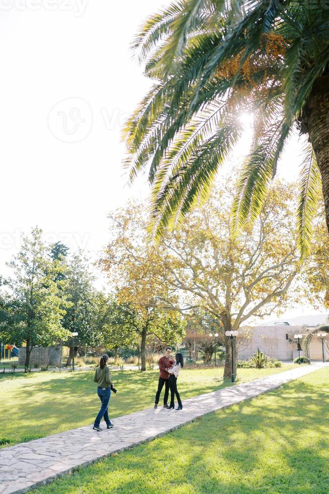 Girl-photographer walks along the path in the park to parents with a child photo