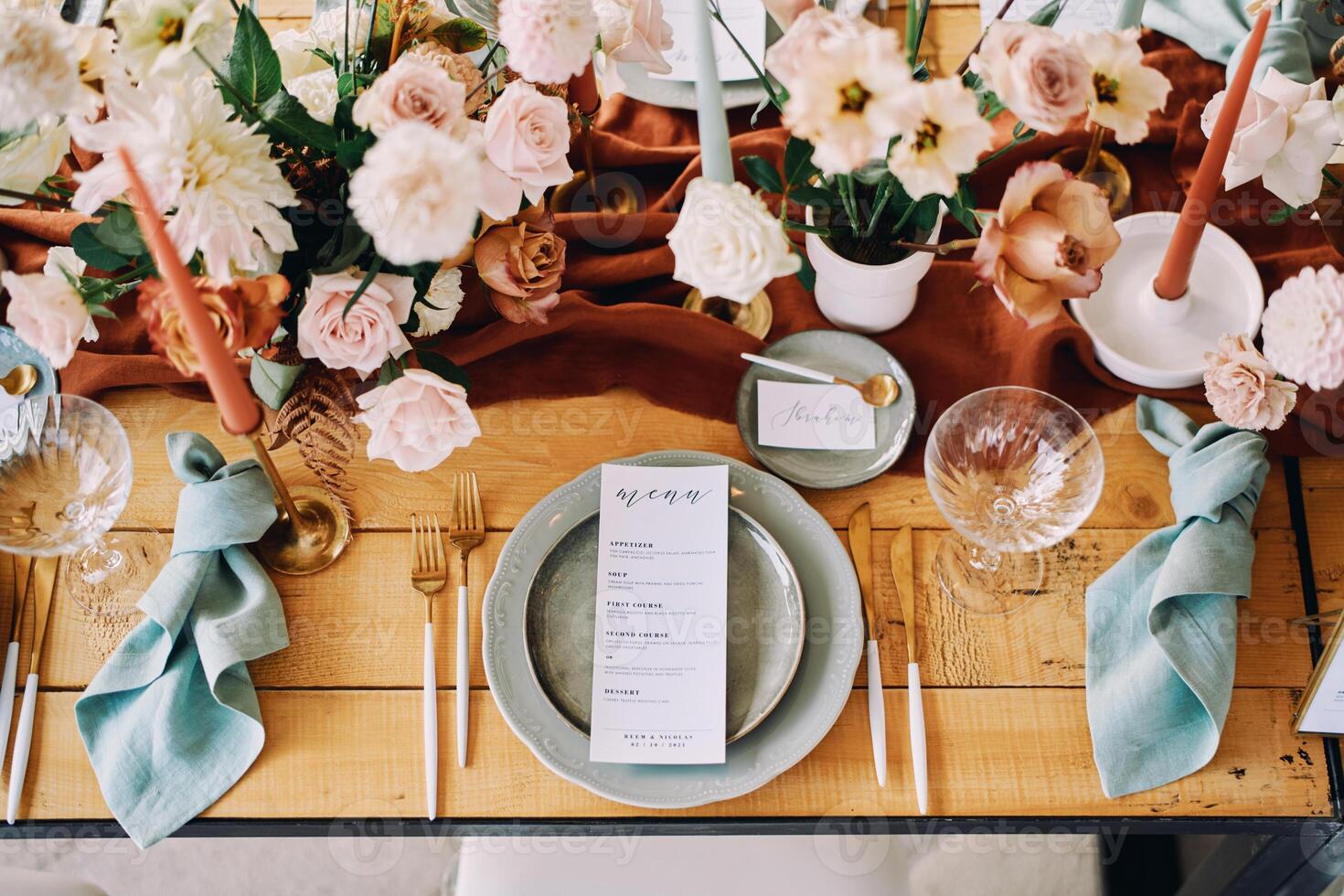 Knotted napkins lie next to a plate with holiday menu opposite bouquets of flowers on the table photo