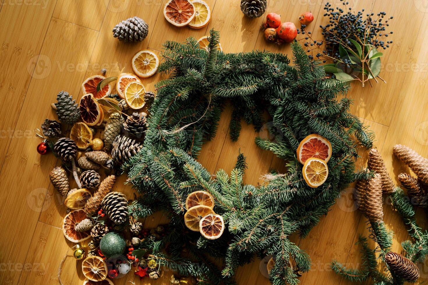 Pieces of dried fruits lie on a round frame of a Christmas wreath surrounded by accessories photo