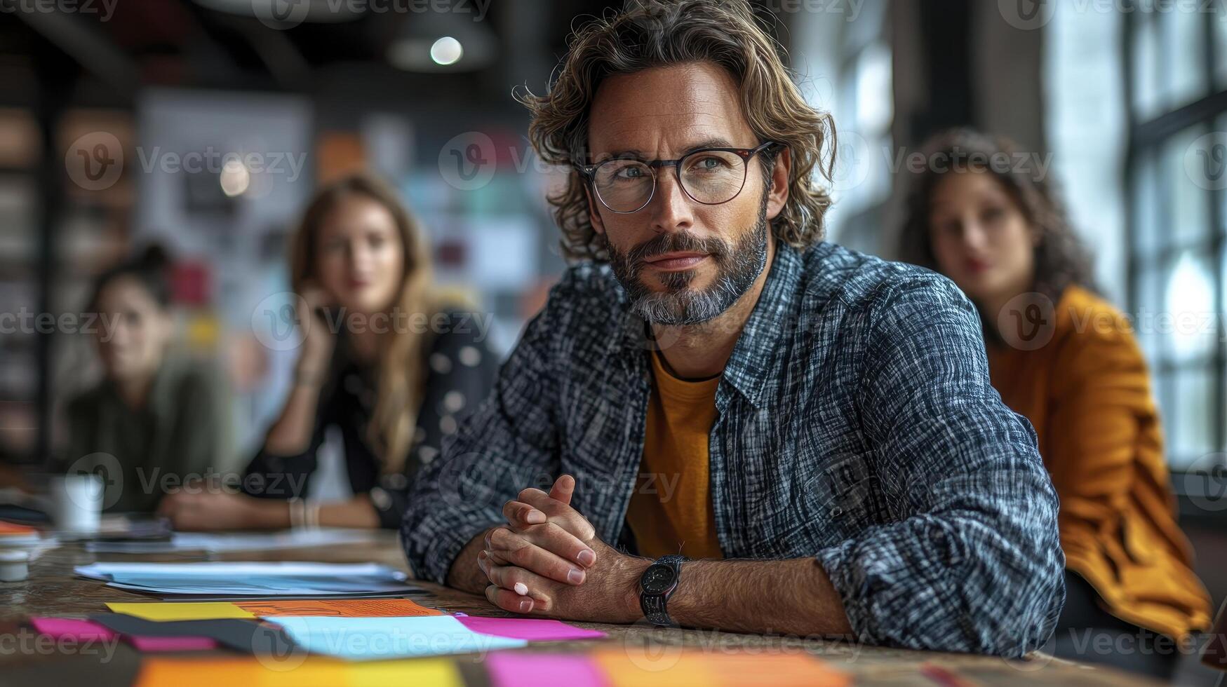 Man sitting at table with other people in background photo