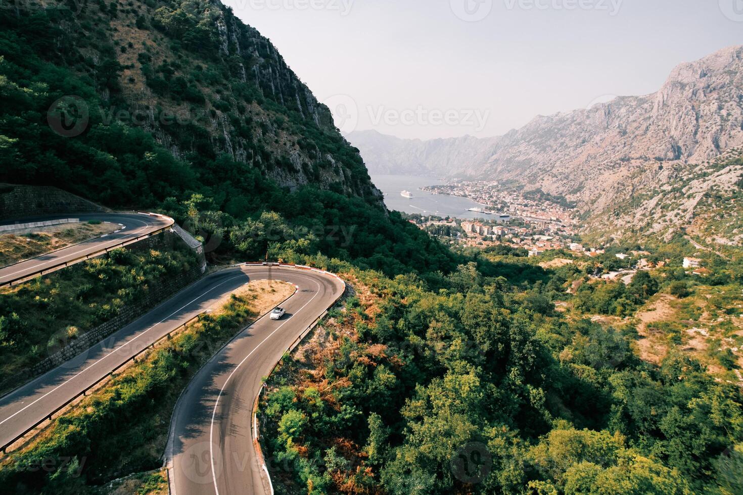 Car drives to the turn of a serpentine road in the mountains above the Bay of Kotor. Montenegro. Aerial view photo